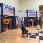Indoor Shopping mall store front with signs that say City Blue Outlet and City Blue Lady Blue